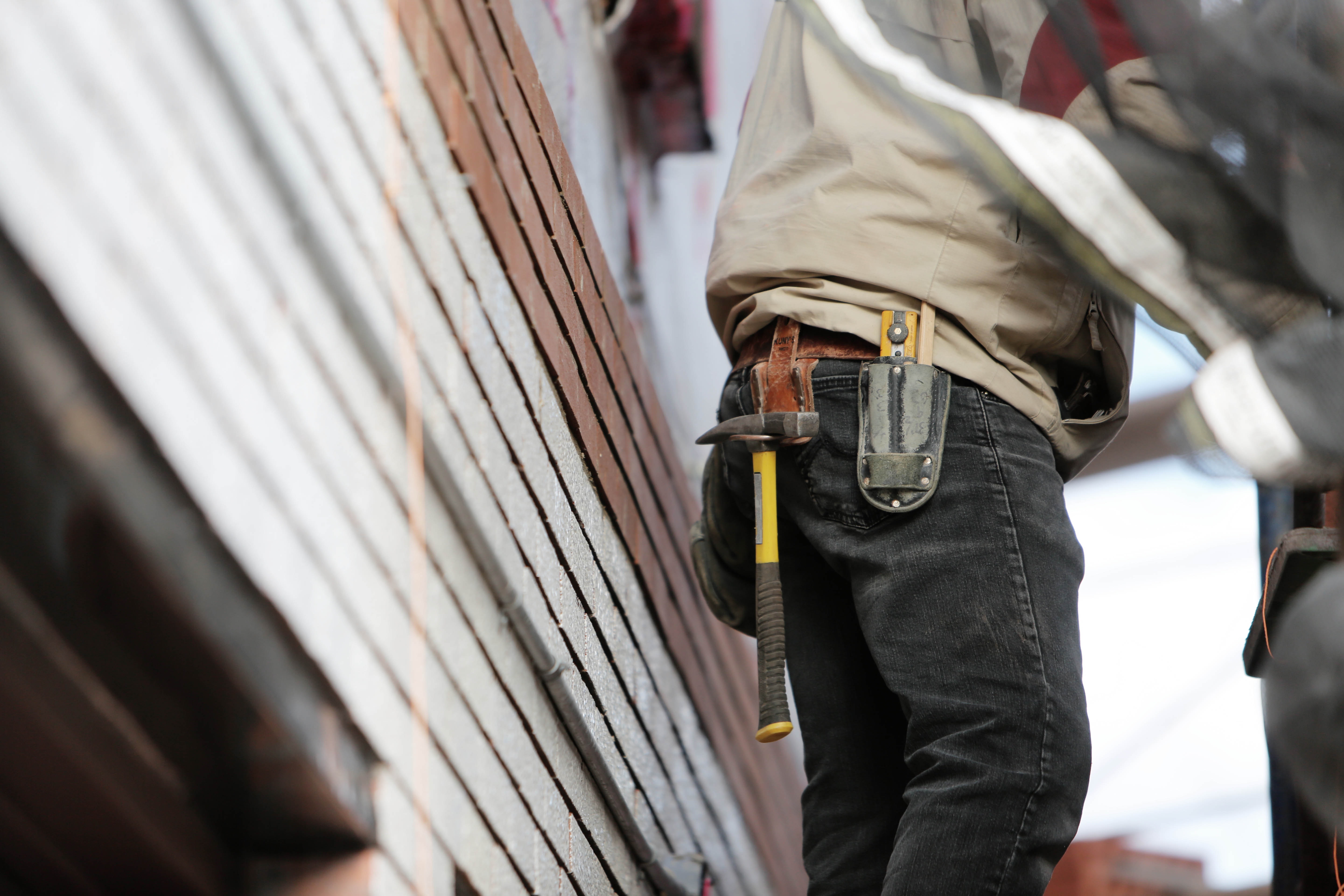Man wearing a tool belt ready to fix a case of rising damp.